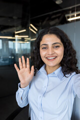 Fototapeta premium Young businesswoman smiling and waving during a video call