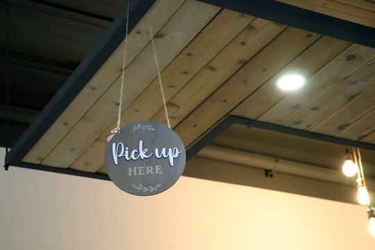 Round slate sign Pick Up HERE suspended from modern wood canopy in restaurant