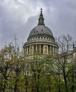 London, United Kingdom - 15 November 2025: View of St Pauls Cathedral dome framed by autumn trees under a cloudy sky.