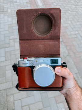 Silver digital camera with a brown leather case held in hand