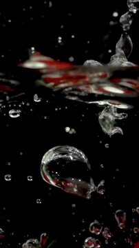 strawberries fruit dropped into water shot in super slow motion in vertical