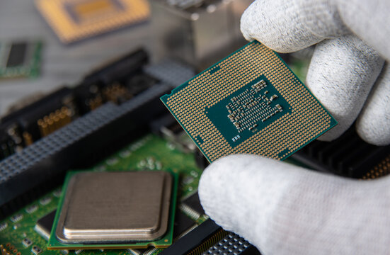 Working on a computer motherboard with a hand holding a CPU and other components nearby