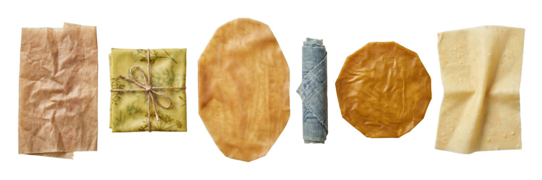 Collection of various eco-friendly food wraps including beeswax paper, a cloth napkin, and brown parchment arranged in a neat row for sustainable living and zero-waste kitchens