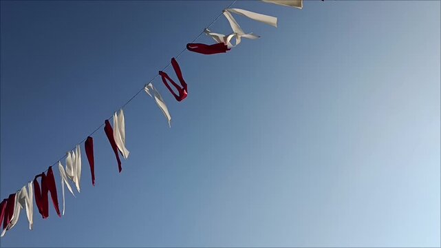 Latvian flag color red and white festive ribbons waving against clear blue sky background, national event horizontal view.
