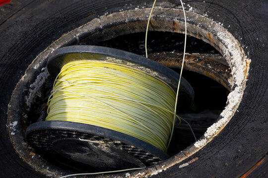 Title:
Yellow fiber optic cable wound on a reel among used industrial equipment