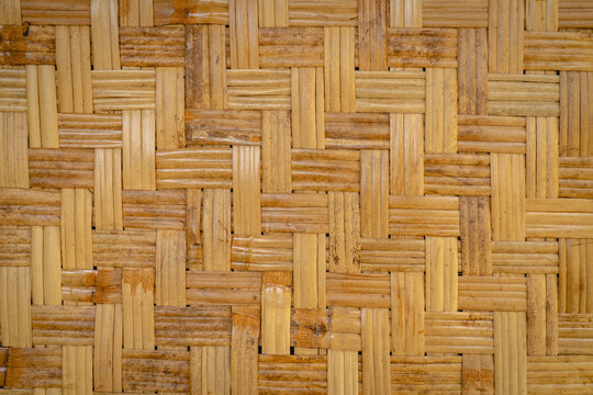 Close-up of woven bamboo strips forming a repetitive geometric pattern with natural brown and beige tones.
