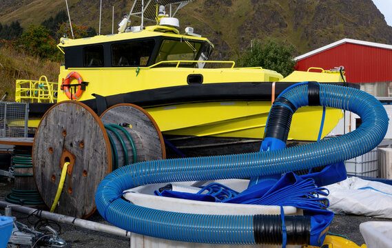 Yellow work boat with hoses and equipment in a Norwegian shipyard
