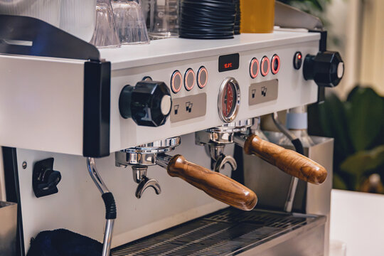 Commercial espresso machine with two portafilters preparing fresh coffee beverages in a modern cafe or restaurant setting