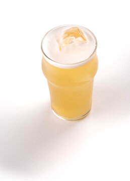 Close-up of a half-pint glass of Radler beer with ice on a wooden table; transparent background with editable shadow.