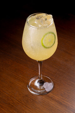 Glass of limoncello spritz with gin, isolated on a wooden table (angled view)