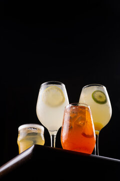 Collection of refreshing, colorful cocktails featuring Aperol and limoncello, shot from a low angle against a black background.