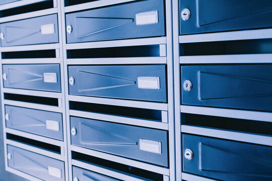 Row of metal mailboxes with name slots and locks in a residential apartment building lobby. Real estate rental concept.