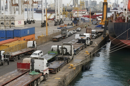 commercial cargo port quay with flatbed trucks and moored ship at durban port, south africa