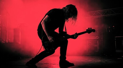 Fototapeta premium Silhouette of a Rock Bassist Performing on Stage with Intense Red Lighting and Smoke Effects at a Live Concert