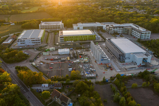 Aerial view of the Kao Data campus featuring modern data center buildings surrounded by lush greenery and trees during golden hour in Harlow, England, United Kingdom.