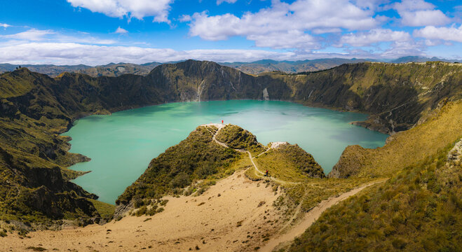 Aerial view of Quilotoa Lake with its vibrant turquoise water inside a volcanic crater, surrounded by steep rugged slopes and hiking trails, Quilotoa, Cotopaxi, Ecuador.