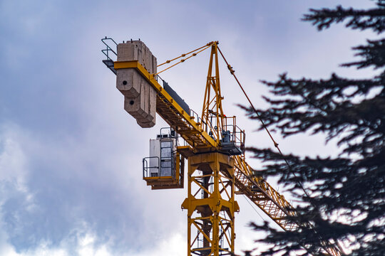 Low angle view of a yellow industrial tower crane against a cloudy sky. This construction-themed image is perfect for architecture, urban development, and engineering projects.