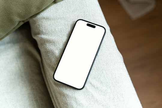 Smartphone with white screen lying on pants indoors