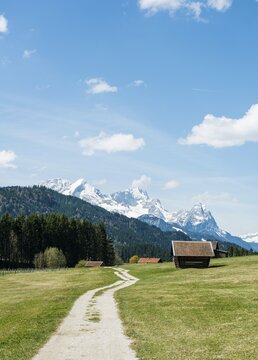 Hay stall in meadow on dirt road with snow-capped Karwendel Mountains, Werdenfelser Land, Upper Bavaria, Bavaria, Germany