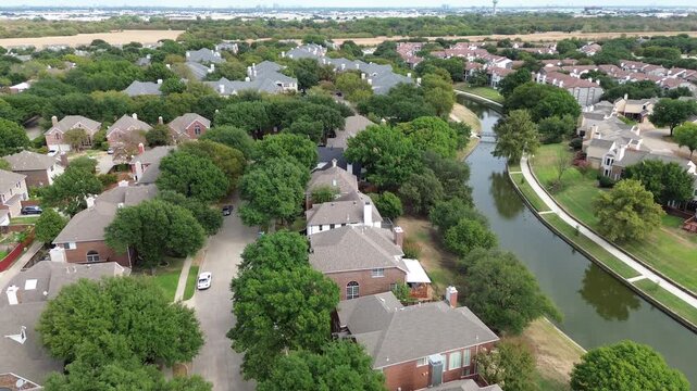 Aerial perspective over Valley Ranch canals highlights winding waterways alongside residential properties. Overhead altitude reveals emerald foliage bordering, Valley Ranch, Irving, TX