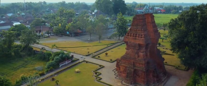 Aerial orbiting drone shot revealing Wringin Lawang, an ancient red brick split gate of the Majapahit empire in Trowulan, Indonesia.