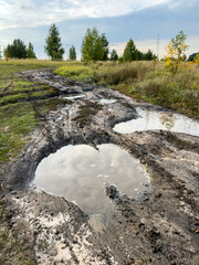 Obraz premium Wet, muddy road with deep puddles and cracked earth