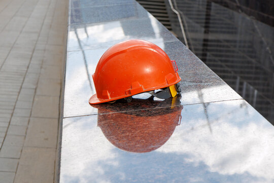 Orange hard hat rests on reflective metal surface