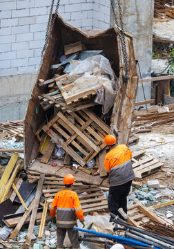 Workers in orange vests handle construction debris