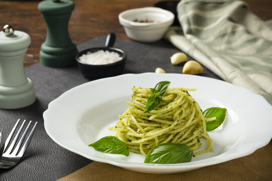 Pasta spaghetti with pesto, basil, garlic and spices on dark table. Italy food.