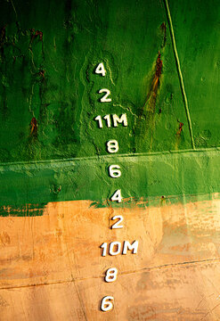 Close-up of draft marks painted on the green hull of a cargo ship