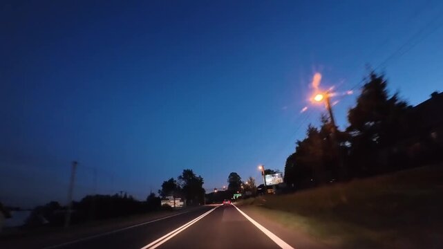 Timelapse of cars Driving On fast road At Sunset Twilight With Streetlights And Evening Sky
