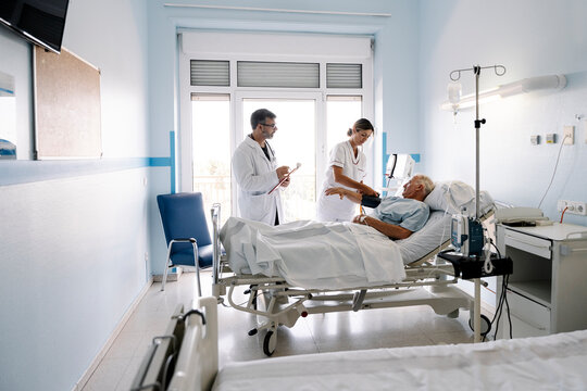 Healthcare team checking on senior patient in hospital ward