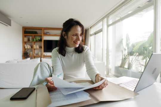 Woman Working at Home With Documents and Laptop in Bright Room