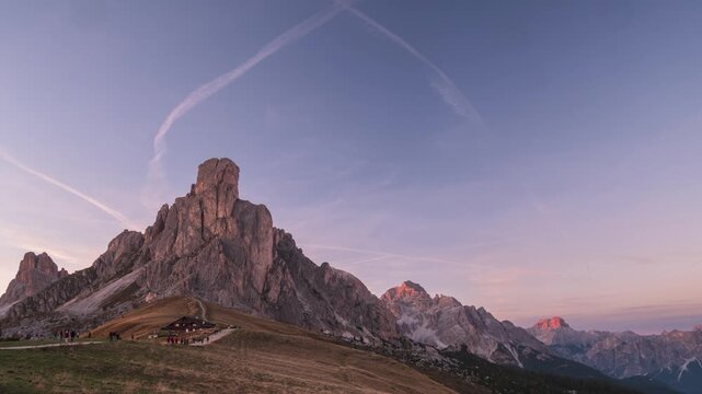 Time lapse of golden sunset light on Ra Gusela peak at Passo Giau, Dolomites, Italy. Shadows creep across an alpine meadow under a clear sky. Serenity, passing time and freedom in the mountains