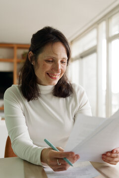 Woman Working at a Table With Papers and a Pen in a Bright Room