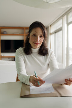 Woman Sitting at Table Working With Papers in Modern Living Room