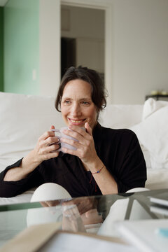 Woman Enjoys Drink While Sitting in Modern Room