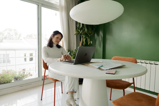 Woman Working on Laptop at Home in Bright Green Room