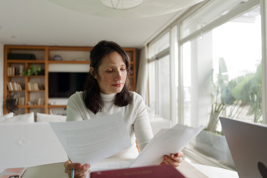 Woman Reviews Paperwork at Home During the Day