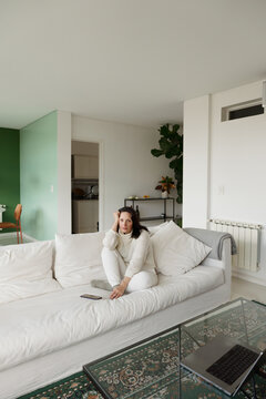 Woman Sitting on a Sofa in a Living Room With Green Walls