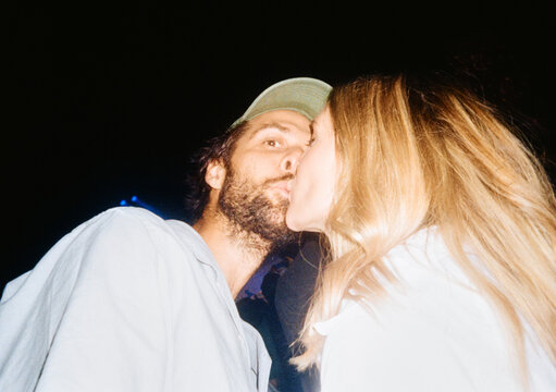Couple Sharing a Kiss During a Night Event