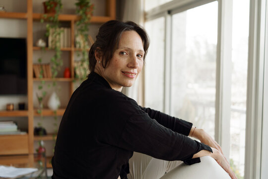 Woman Sitting by Large Window in a Bright Room