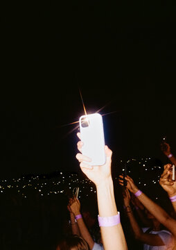Crowd Members Hold up Phones at a Concert During the Night