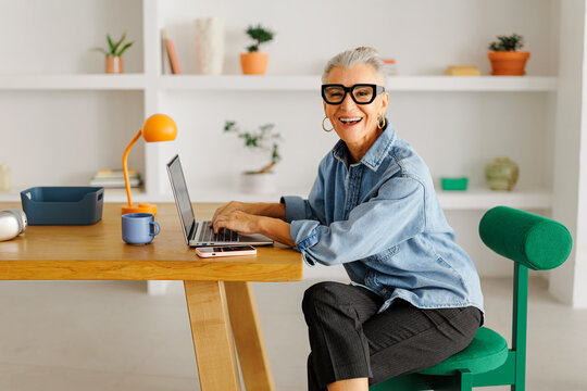 Mature woman smiling working remote on laptop