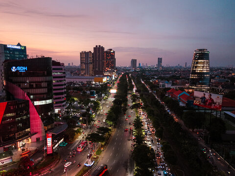 Aerial view of the urban skyline and busy traffic on a main road at twilight in Surabaya, East Java, Indonesia.