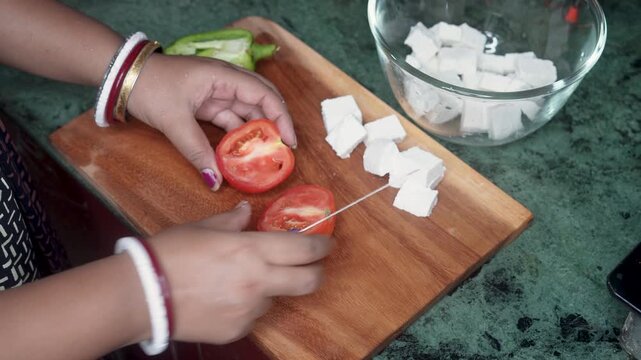 Indian Woman hands slicing fresh tomato with knife on cutting board in kitchen counter at home. Cooking healthy food from vegetables.