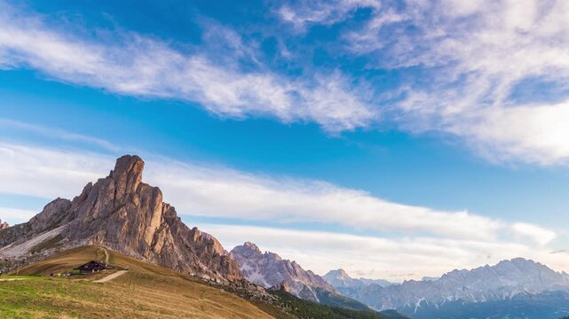Time lapse of golden sunrise light on Ra Gusela peak at Passo Giau, Dolomites, Italy. Shadows creep across an alpine meadow under a clear sky. Serenity, passing time and freedom in the mountains