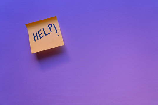 A yellow sticky note attached to a surface with the word help conveying the idea of aid, urgency, or a request for assistance.