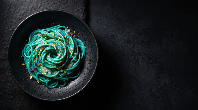 Turquoise Spirulina Pasta Swirl With Gold Leaf And Spherified Pearls In Dark Bowl