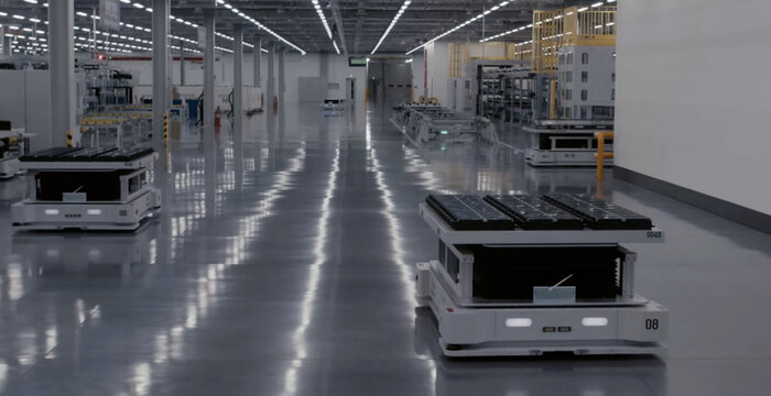 View of automated guided vehicles moving through a modern industrial factory with reflective floors and assembly lines in Jilin City, Jilin Province, China.